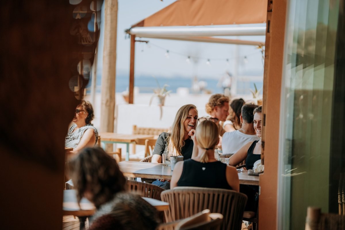 La terraza de Petit Nola a mediodía: mesas llenas, guirnaldas de luces y el mar de Portixol al fondo.